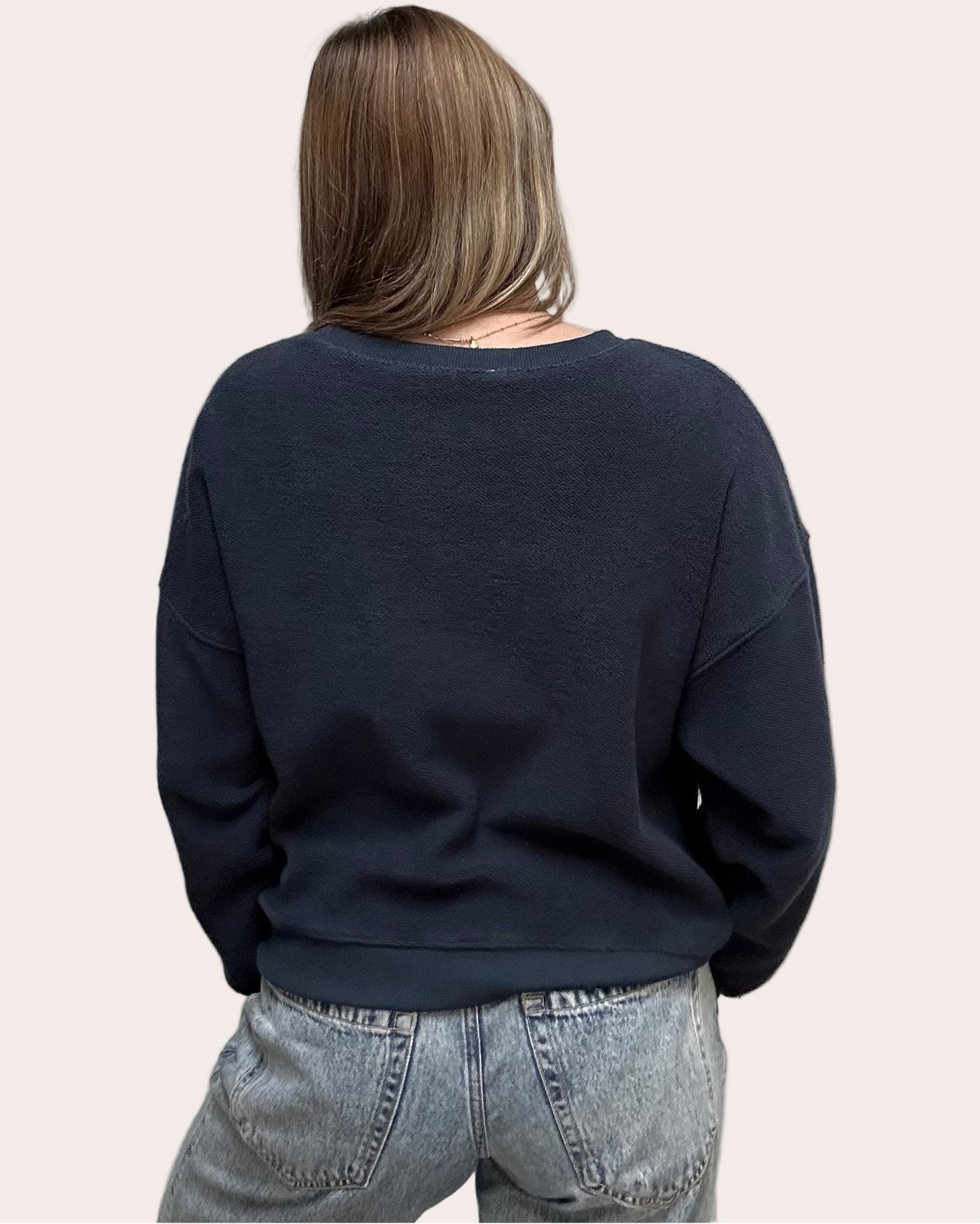 Cozy pullover sweatshirt with a relaxed fit, dropped dolman sleeves, and a bold contrast stripe detail, photographed on a soft-linen background.