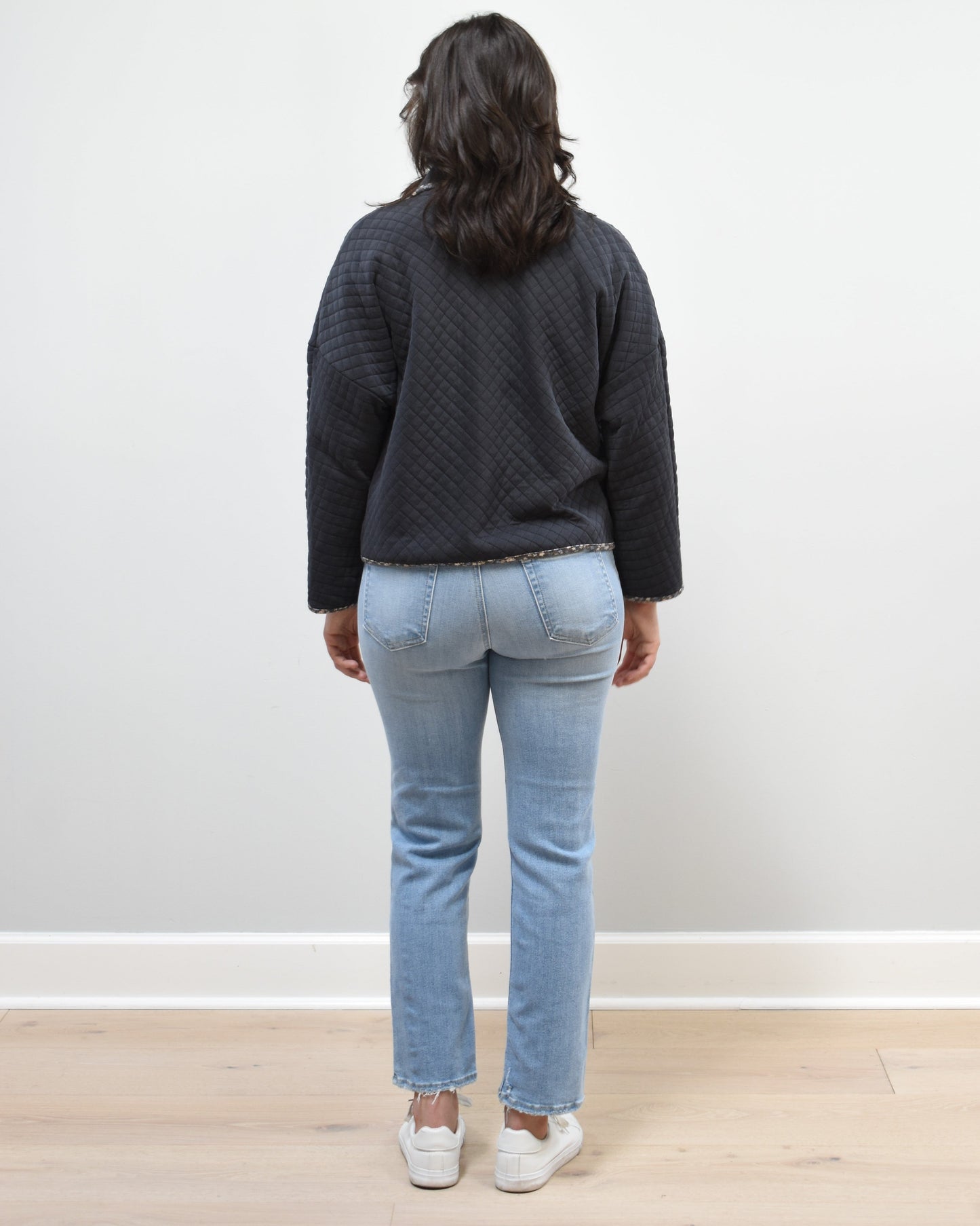 Back view of the quilted floral contrast zip-up jacket showing the mock neck, side pockets, and feminine detailing.