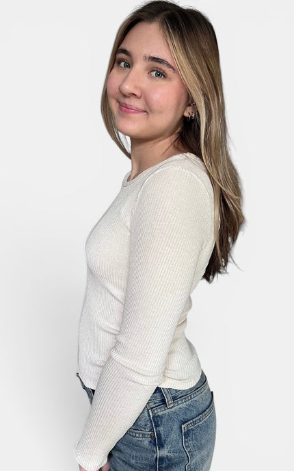 Cream-colored ribbed long-sleeve knit sweater and blue jeans against a plain white studio background.