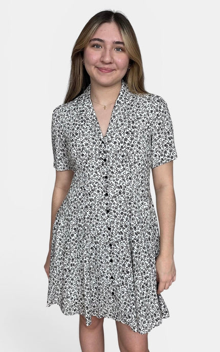 Short-sleeve button-front dress with an allover black and white floral pattern against a light gray studio background.