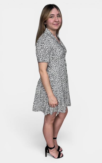 Short-sleeve collared dress with a black and white abstract floral pattern, standing against a light gray studio background.