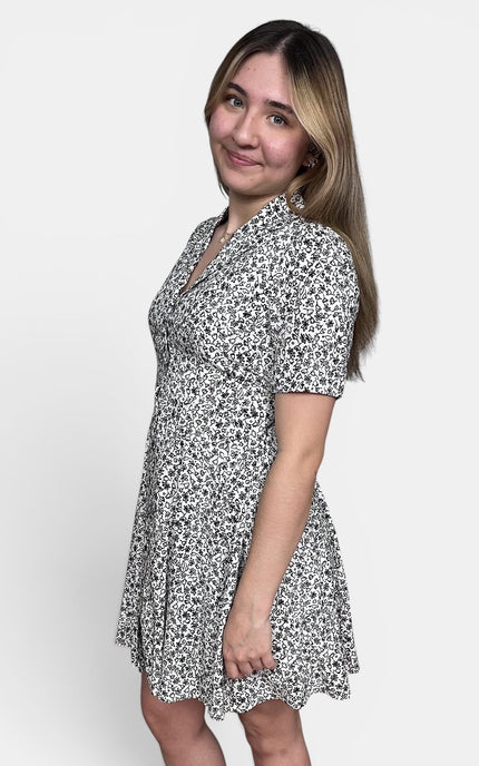Short-sleeve V-neck dress with a black and white floral pattern, standing against a light gray studio background.