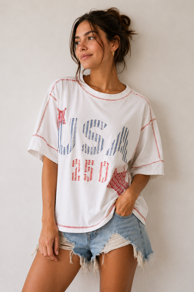Woman wearing a white t-shirt with 'USA 250' print and denim shorts against a plain background