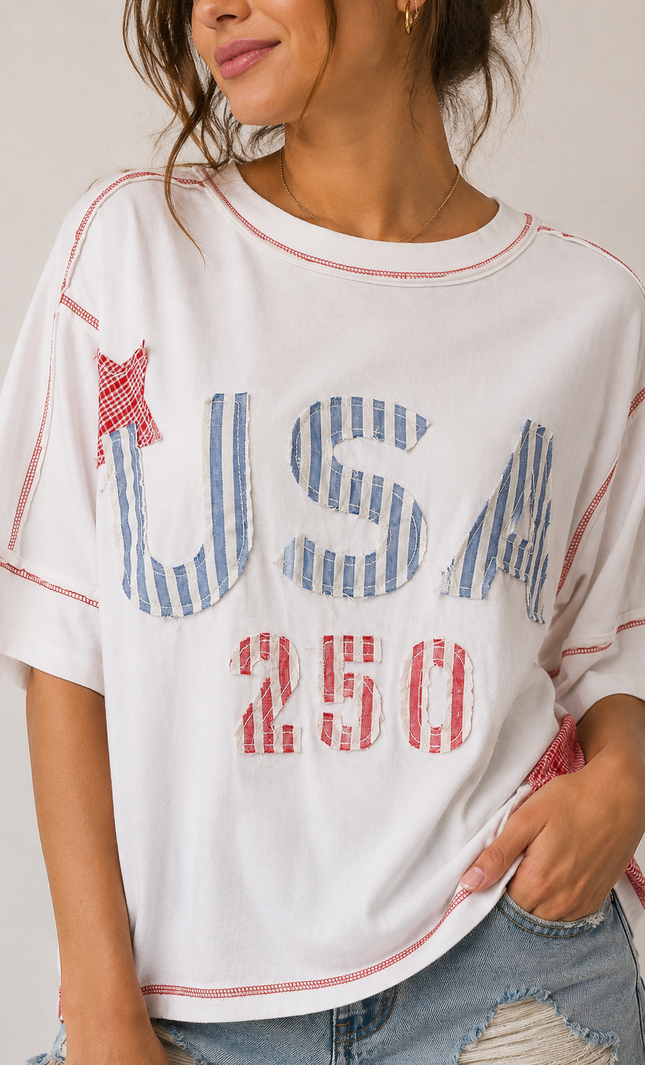 Person wearing a white t-shirt with 'USA 250' print and denim shorts on a plain background