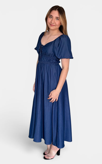 Side angle view of a French blue midi dress featuring a smocked bodice, sweetheart neckline, and flowy skirt.