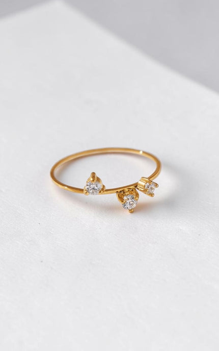 A clear macro shot focusing on the three brilliant cubic zirconia stones and the thin, dainty profile of the stainless steel band.