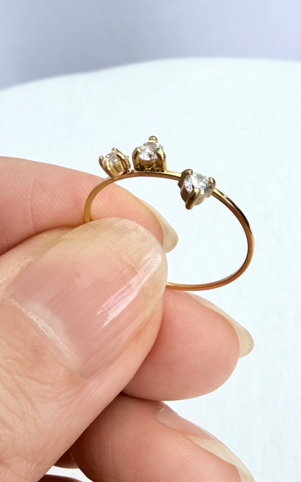 A dainty, waterproof stainless steel three-stone ring displayed in a hand to show its ultra-lightweight design and delicate scale.
