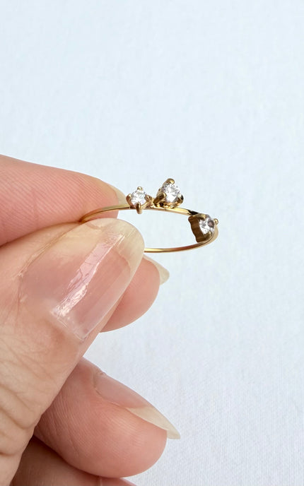 A dainty, waterproof stainless steel three-stone ring displayed in a hand to show its ultra-lightweight design and delicate scale.