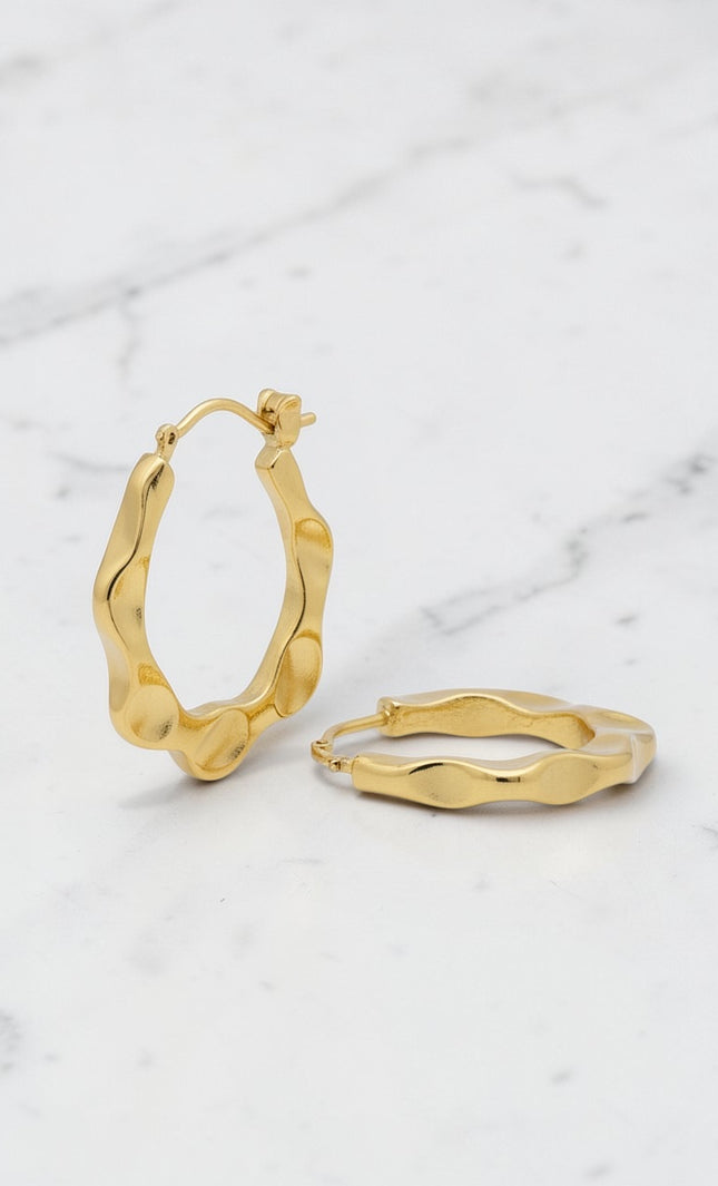 Gold hoop earrings on a marble surface