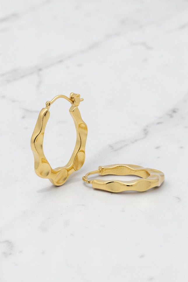 Gold hoop earrings on a marble surface
