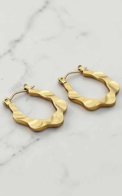 Gold hoop earrings on a marble surface