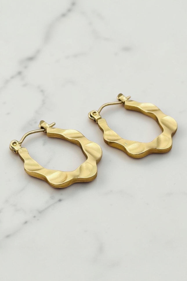 Gold hoop earrings on a marble surface