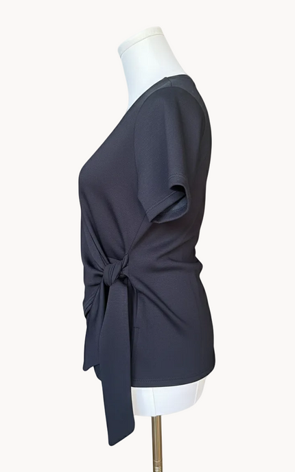 Black top with a knot detail on a mannequin against a light pink background