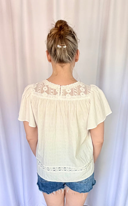 Back view of the white Aurelia blouse, highlighting a classic buttoned keyhole closure at the neckline and a loose, comfortable fit in 100% breathable cotton.