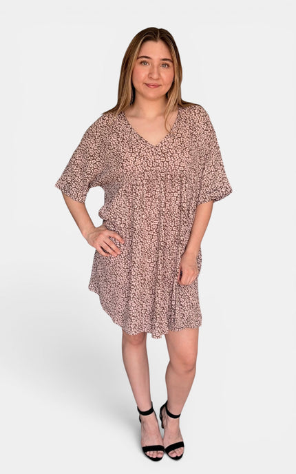 Short-sleeve, V-neck babydoll dress with an all-over pink and beige floral pattern, paired with black strappy high-heeled sandals, against a light gray studio background.