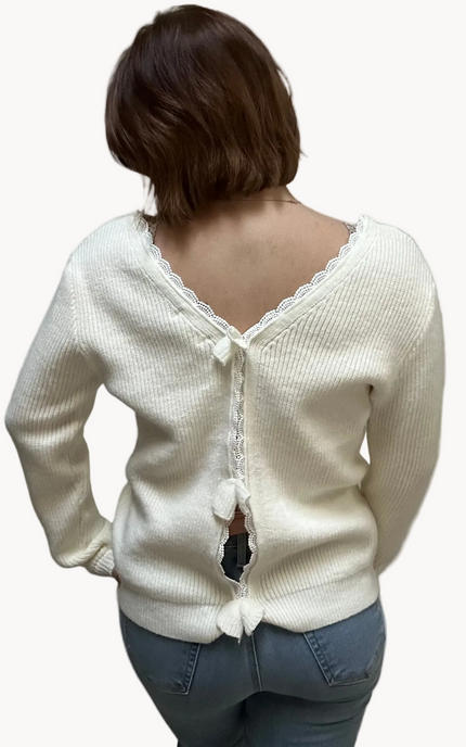 Off-white ribbed sweater with lace-trim V-neckline and oversized bow detail draping down the back, photographed on a Soft Linen background for Justyna Grace Boutique.