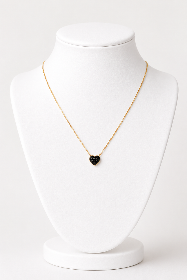 A delicate gold chain necklace with a small black heart-shaped pendant, displayed on a white jewelry bust against a clean white background.