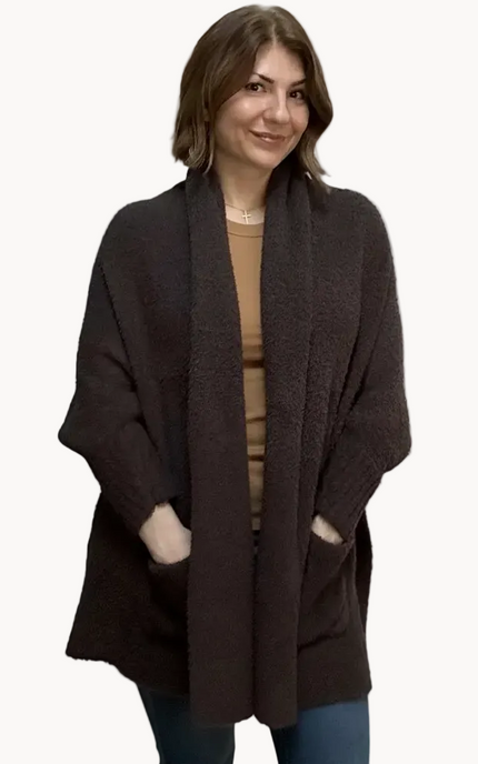 Espresso brown boucle knit poncho with open-front shawl collar, asymmetrical hem, fitted long sleeves, and front patch pockets – relaxed flowing silhouette – front view on soft linen background – Justyna Grace Boutique