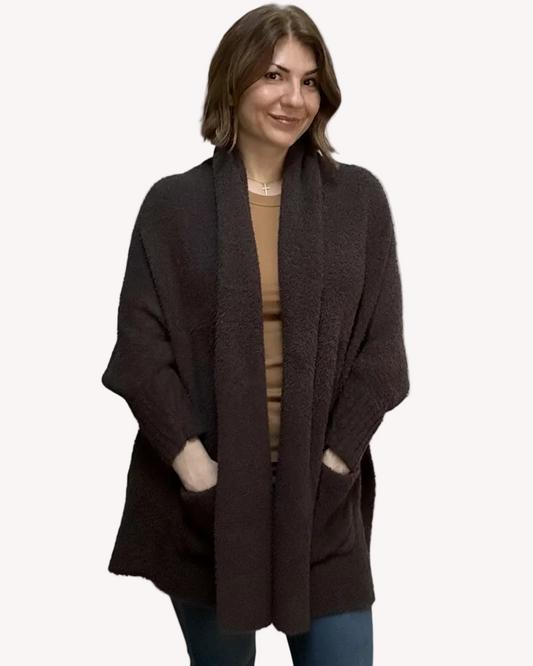 Espresso brown boucle knit poncho with open-front shawl collar, asymmetrical hem, fitted long sleeves, and front patch pockets – relaxed flowing silhouette – front view on soft linen background – Justyna Grace Boutique