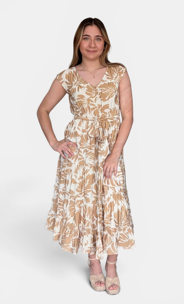 Sleeveless midi dress with a beige and white tropical leaf pattern, standing against a light gray studio background.