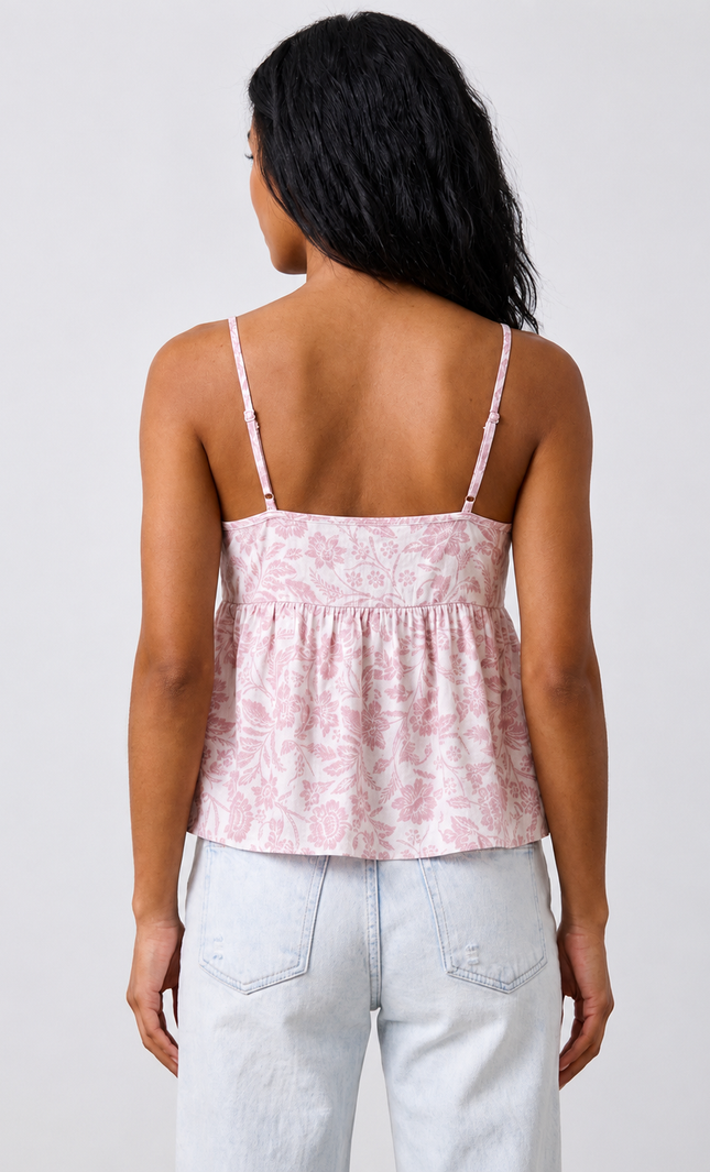 Woman wearing a pink patterned top and light blue jeans on a white background