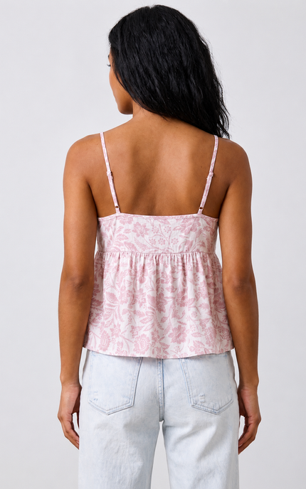 Woman wearing a pink patterned top and light blue jeans on a white background
