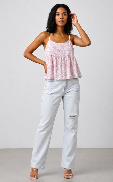 Woman wearing a pink floral top and light blue jeans against a white background