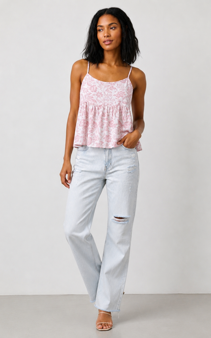 Woman wearing a pink lace top and light blue jeans against a white background