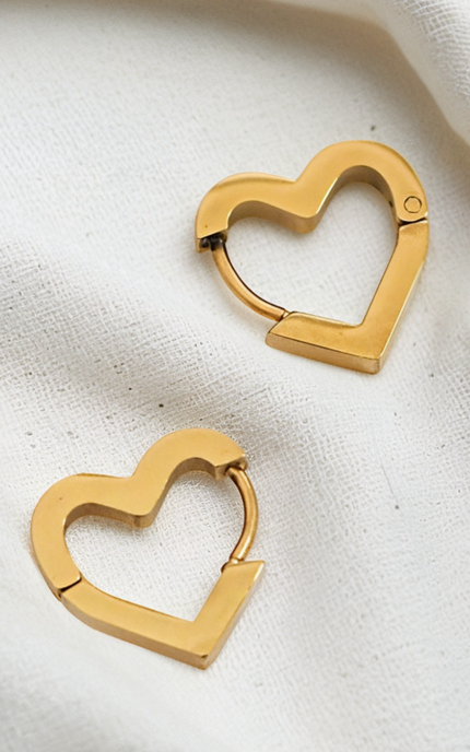 Gold heart-shaped hoop earrings on a light fabric background
