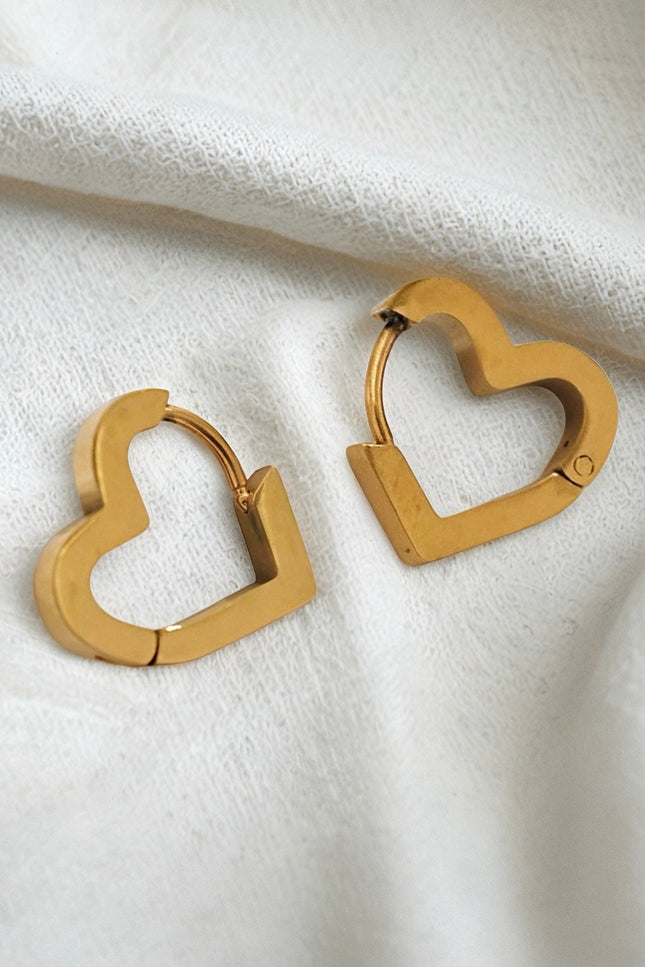 Gold heart-shaped hoop earrings on a white fabric background