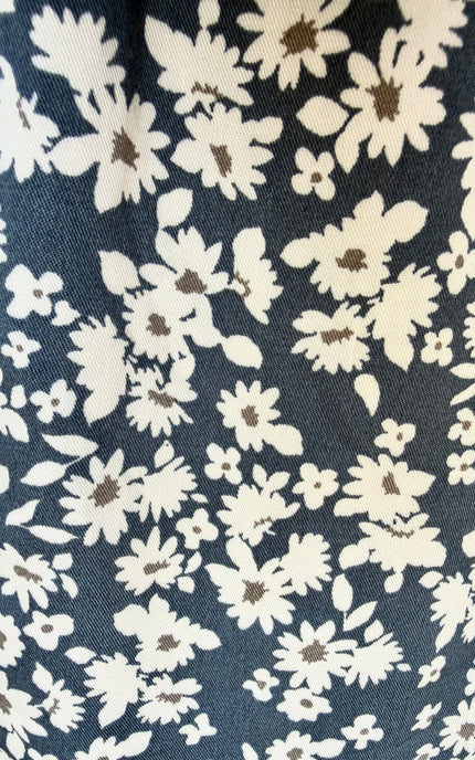 Close-up of a navy blue fabric with an all-over cream and brown floral print.