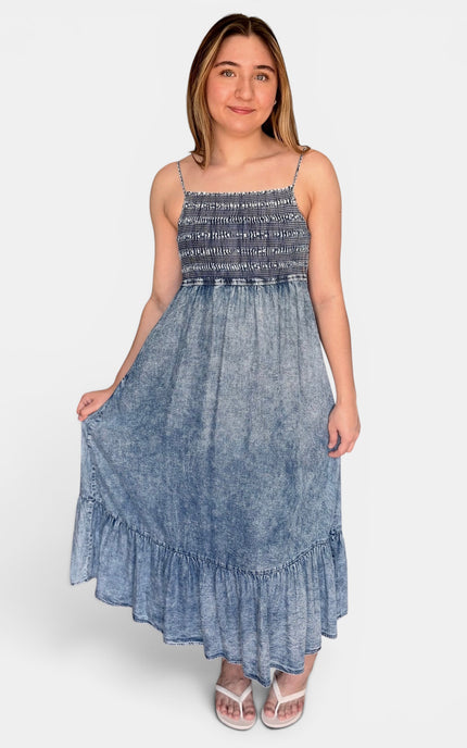 Woman wearing a sleeveless Tencel midi dress with a smocked bodice and tiered skirt.