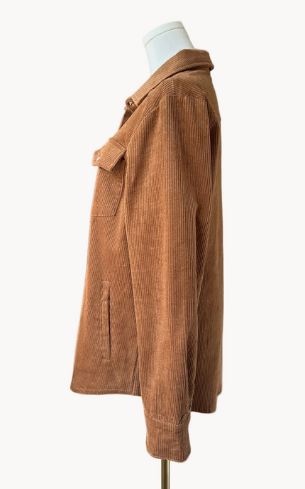 Soft corduroy button-down shacket with a relaxed fit and side pockets, shown in a neutral tone against a clean soft-linen background, styled as a cozy layering piece.