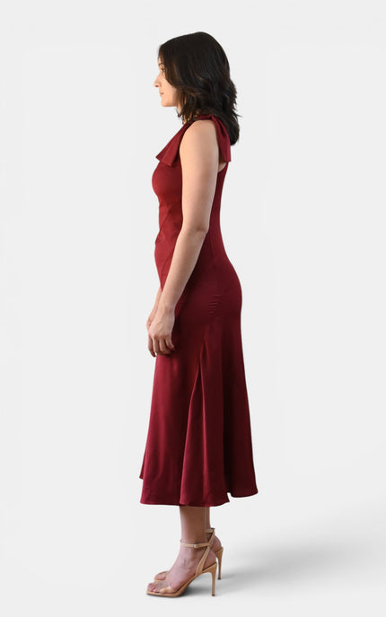 Side view of a cranberry one shoulder midi dress with oversized bow shoulder and flattering flared silhouette.