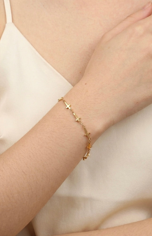 Cross‑station bracelet worn alone for a quiet, meaningful everyday look.