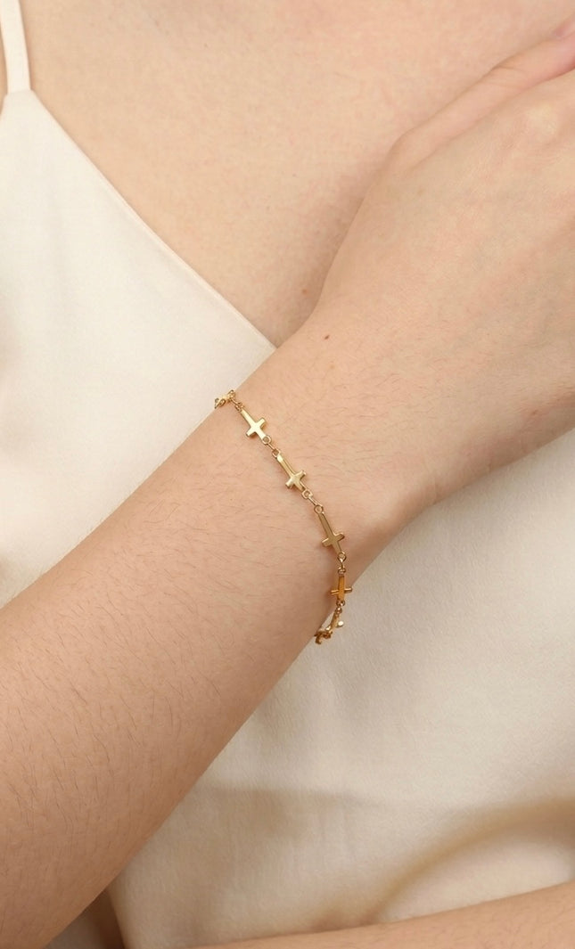 Cross‑station bracelet worn alone for a quiet, meaningful everyday look.