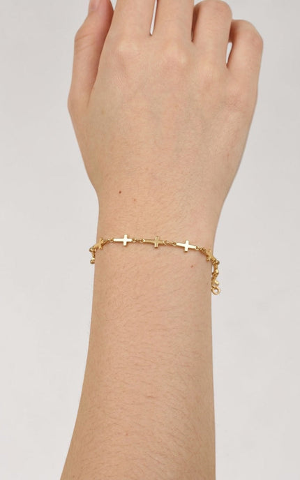 Cross‑station bracelet worn alone for a quiet, meaningful everyday look.