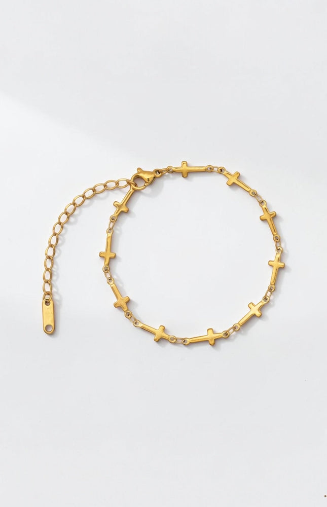 Front view of delicate gold cross‑station bracelet with evenly spaced charms along a slim cable chain.