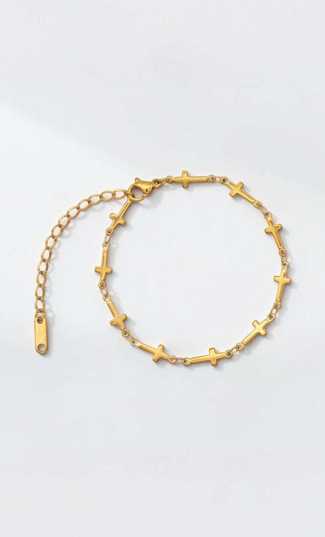 Front view of delicate gold cross‑station bracelet with evenly spaced charms along a slim cable chain.