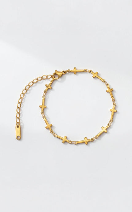 Front view of delicate gold cross‑station bracelet with evenly spaced charms along a slim cable chain.