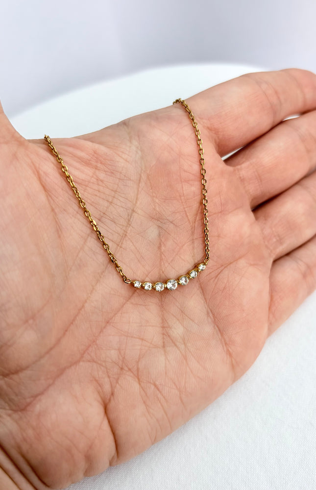 Zircon bar necklace resting in an open palm, showing delicate scale and subtle sparkle.
