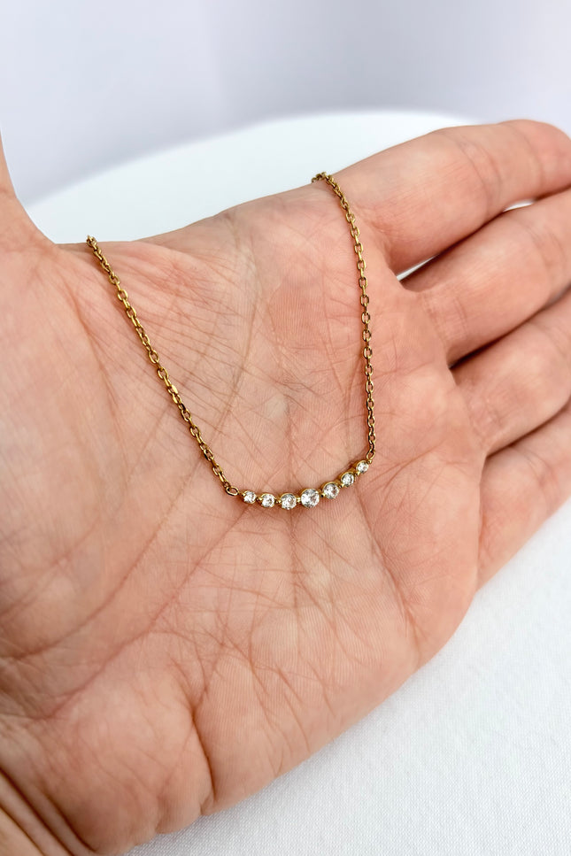Zircon bar necklace resting in an open palm, showing delicate scale and subtle sparkle.