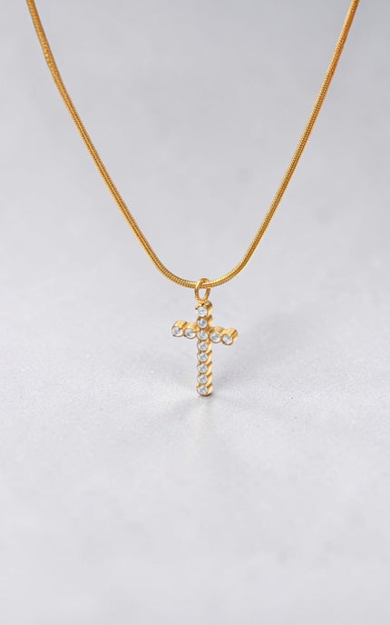 Delicate gold necklace featuring a crystal-studded cross pendant.
