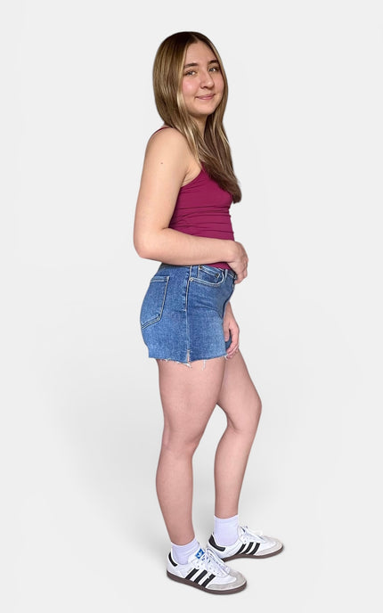 Medium-wash high-rise denim shorts with a raw cut-off hem and soft stretch fabric.