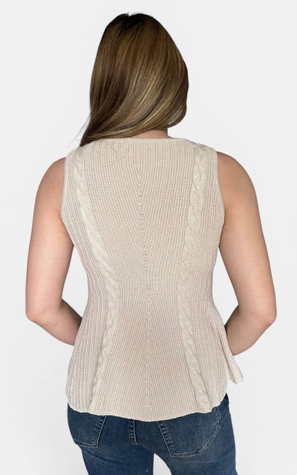 A woman viewed from the back wearing a sleeveless ribbed knit peplum top in a light beige or cream color, paired with blue jeans, against a plain light gray studio background.