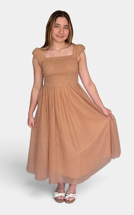  Woman wearing a Swiss dot midi dress with a smocked bodice and flutter cap sleeves