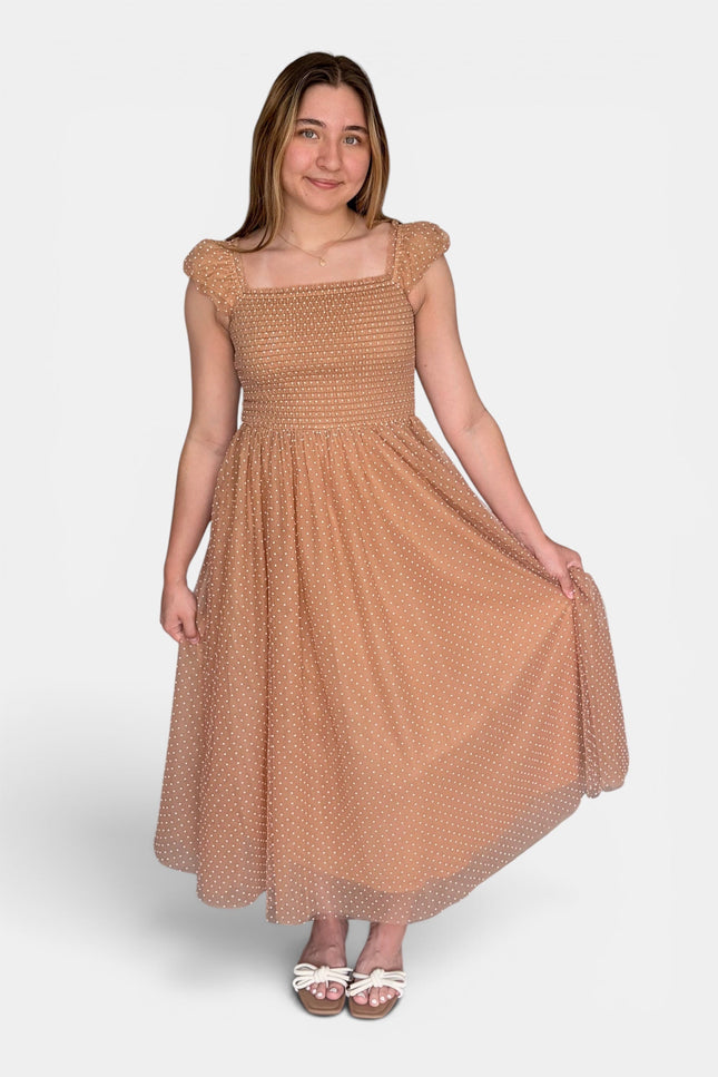  Woman wearing a Swiss dot midi dress with a smocked bodice and flutter cap sleeves