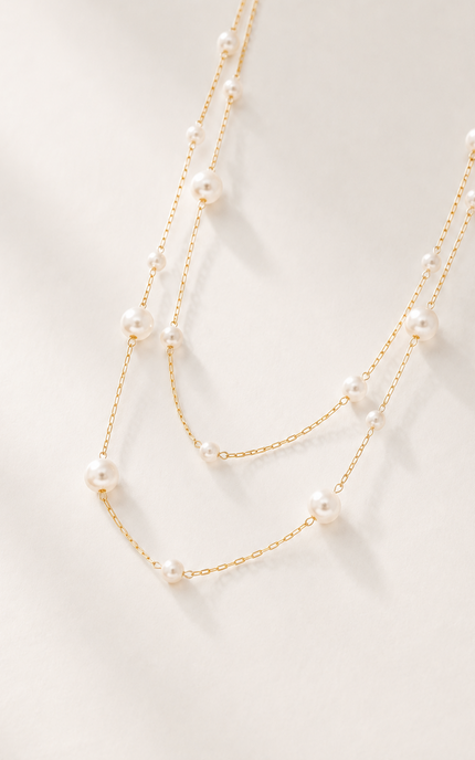 Double strand 18k gold paperclip chain necklace with mixed size imitation pearl stations displayed on a light neutral background, showcasing the layered design, delicate paperclip chains, and elegant pearl accents.
