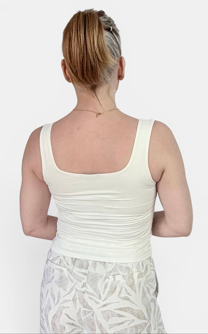 A woman shown from the back wearing a ivory-colored scoop-neck tank top and a light gray patterned skirt, set against a plain light gray background.