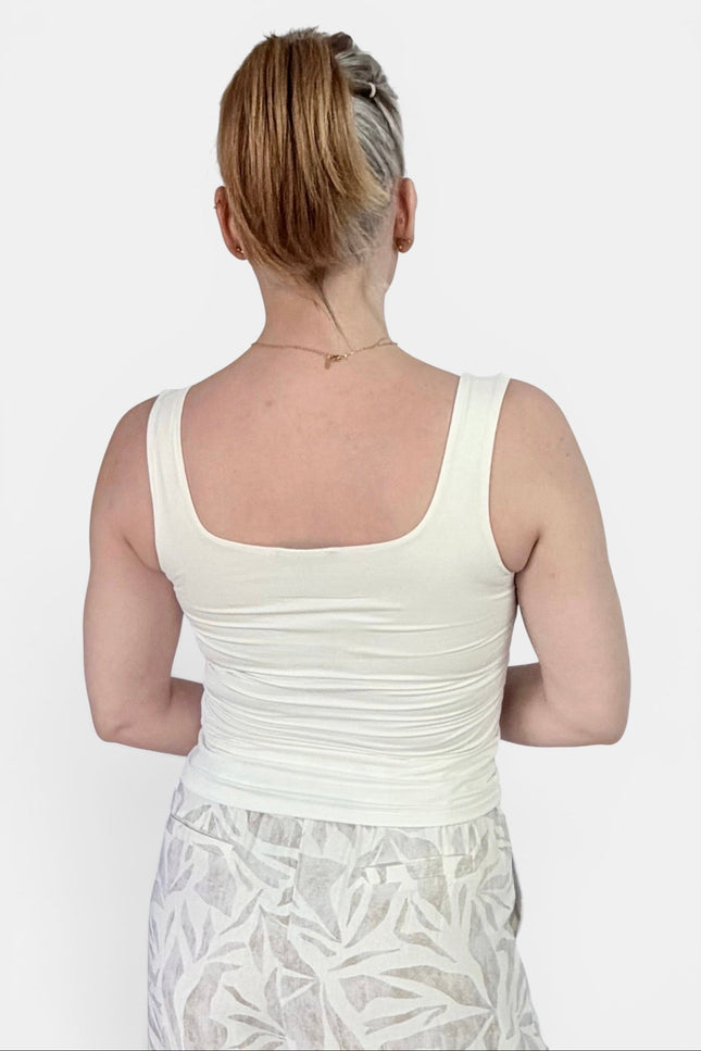 A woman shown from the back wearing a ivory-colored scoop-neck tank top and a light gray patterned skirt, set against a plain light gray background.